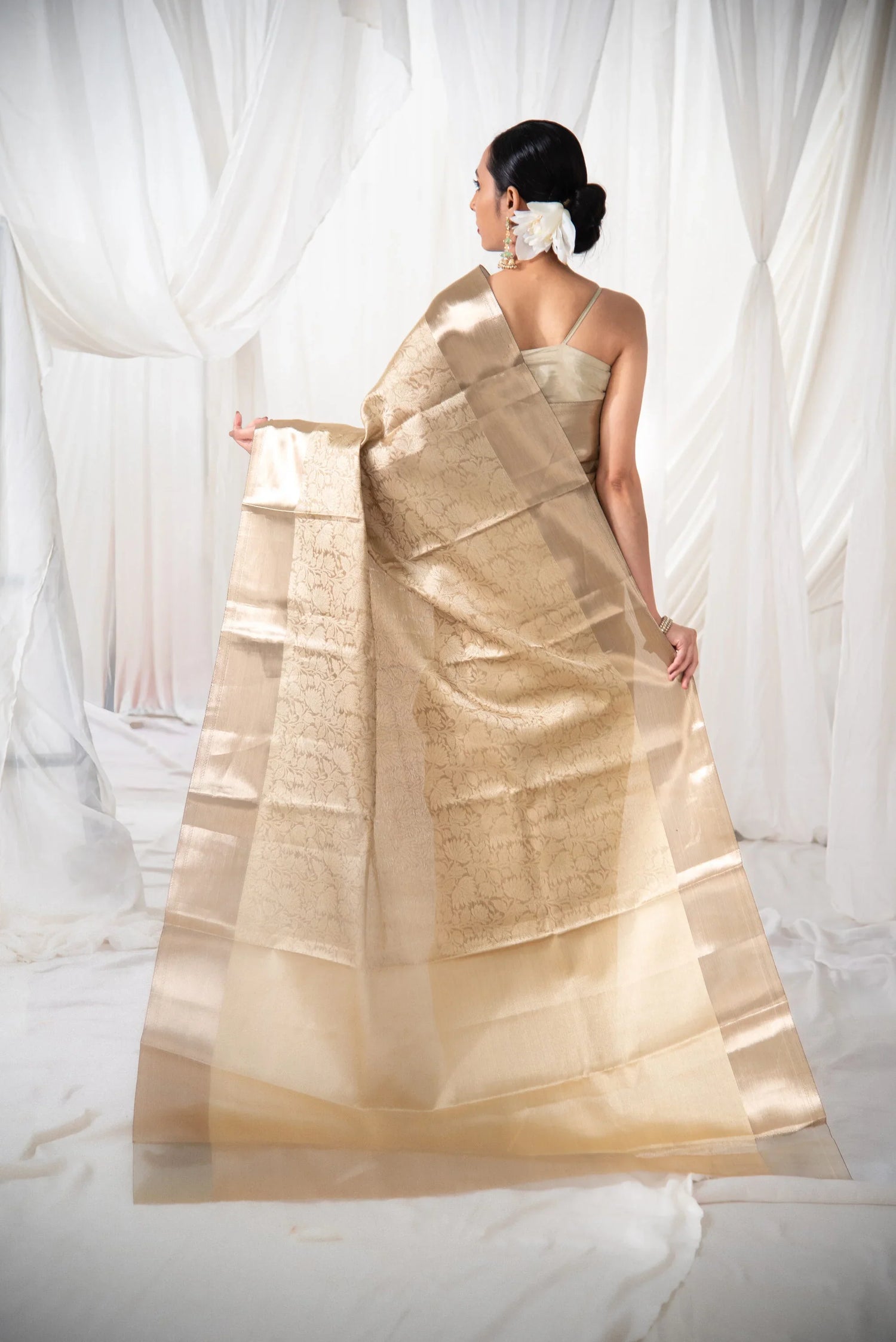 Woman in gold Banarasi tissue silk saree with floral pattern, elegant back view