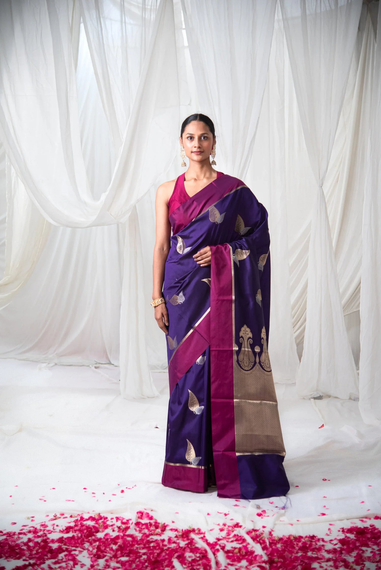 Woman wearing a purple Banarasi silk saree with gold motifs and magenta border