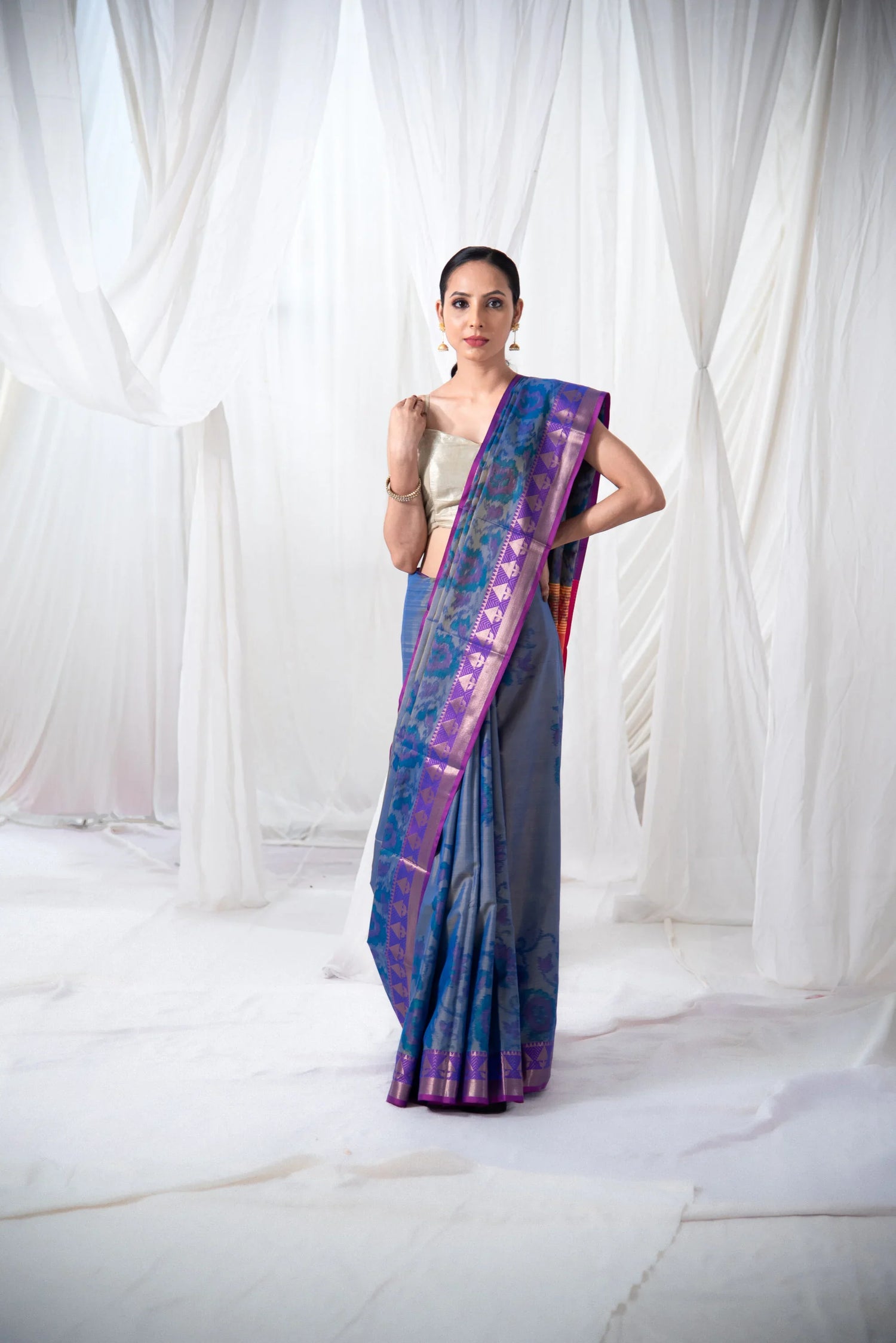 Woman wearing blue Ikkat silk saree with purple border, traditional Indian attire