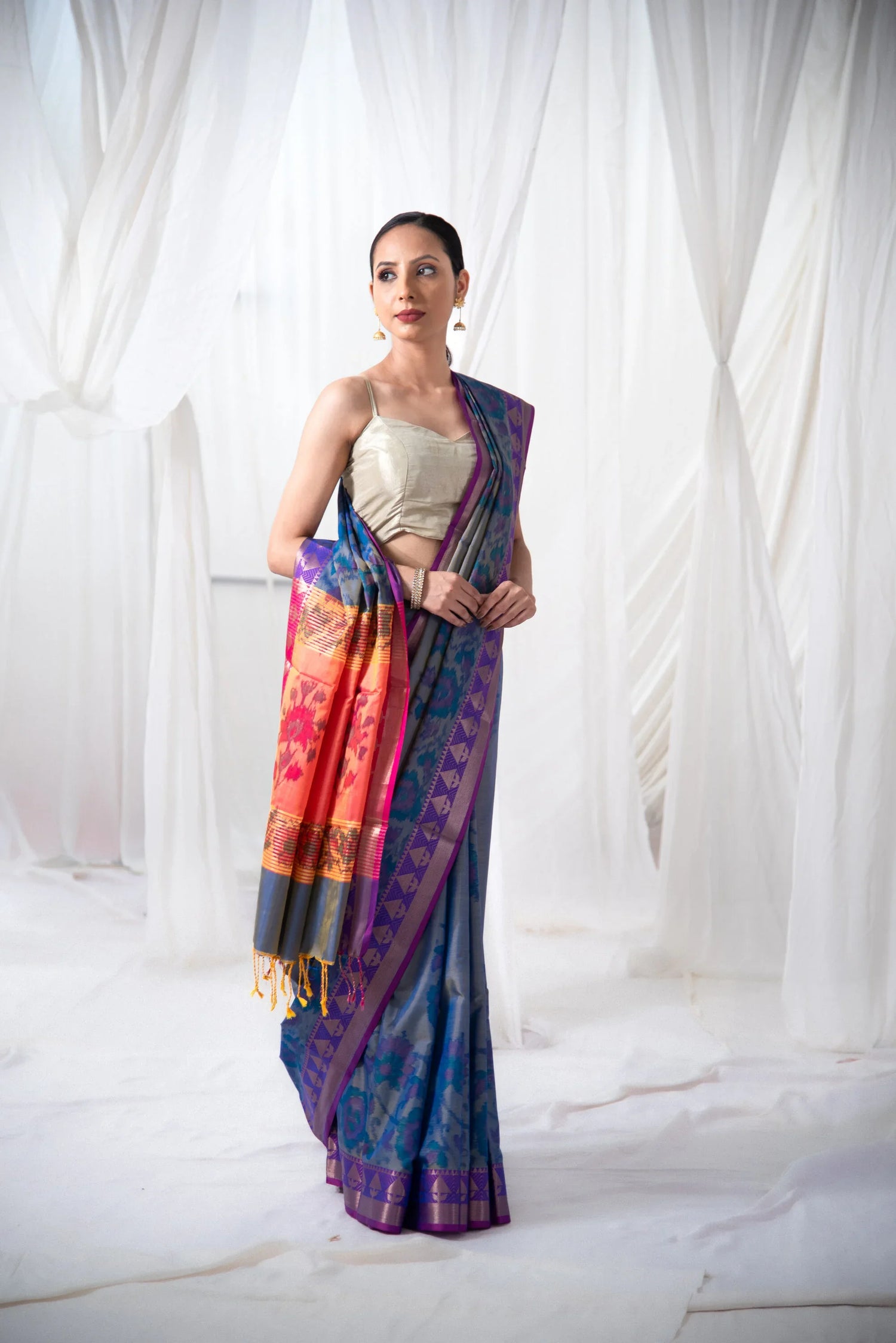 Woman wearing blue and orange Ikkat Banarasi silk saree with gold blouse, elegant setting