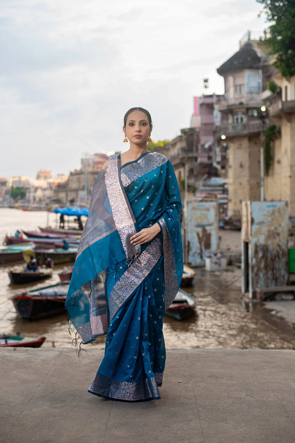 Woman wearing blue Banarasi acrylic cotton saree with zari work by riverside