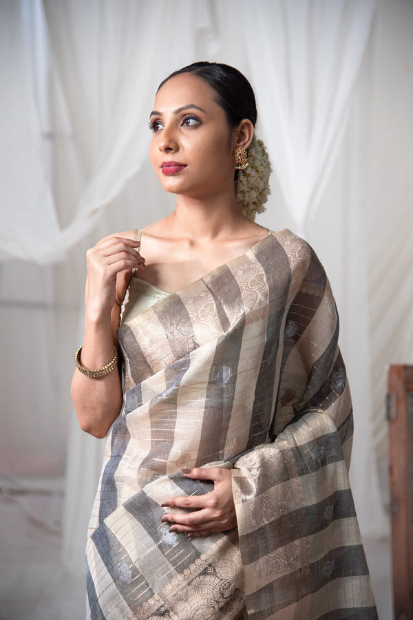 Woman wearing elegant striped Banarasi cotton linen saree with floral gold jewelry — alternate view (back / drape detail)