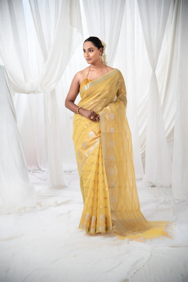Woman in yellow Banarasi cotton linen silk saree with gold border and floral motifs