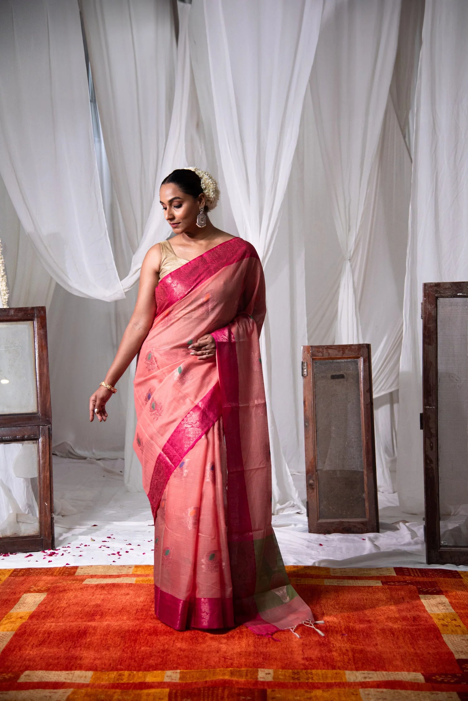 Woman wearing pink Banarasi cotton saree with dual-tone tassels, standing indoors