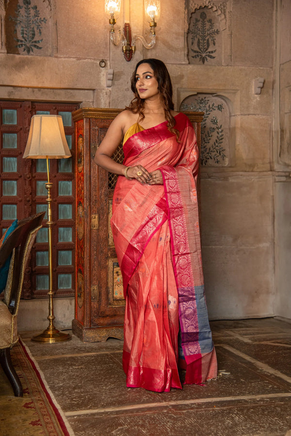 Woman wearing a peach Banarasi cotton silk saree with pink border and traditional decor