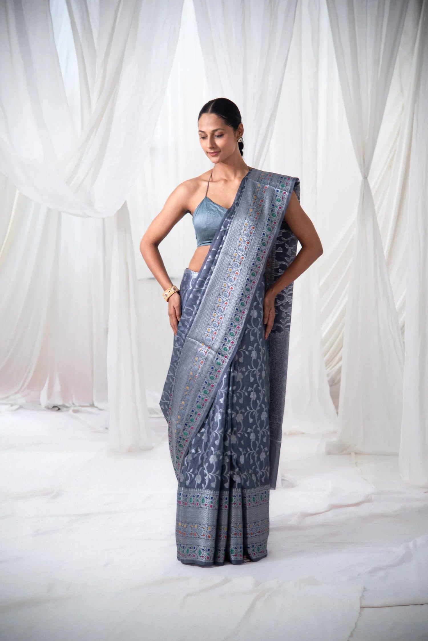 Woman modeling grey Banarasi silk saree with intricate silver and colorful woven patterns