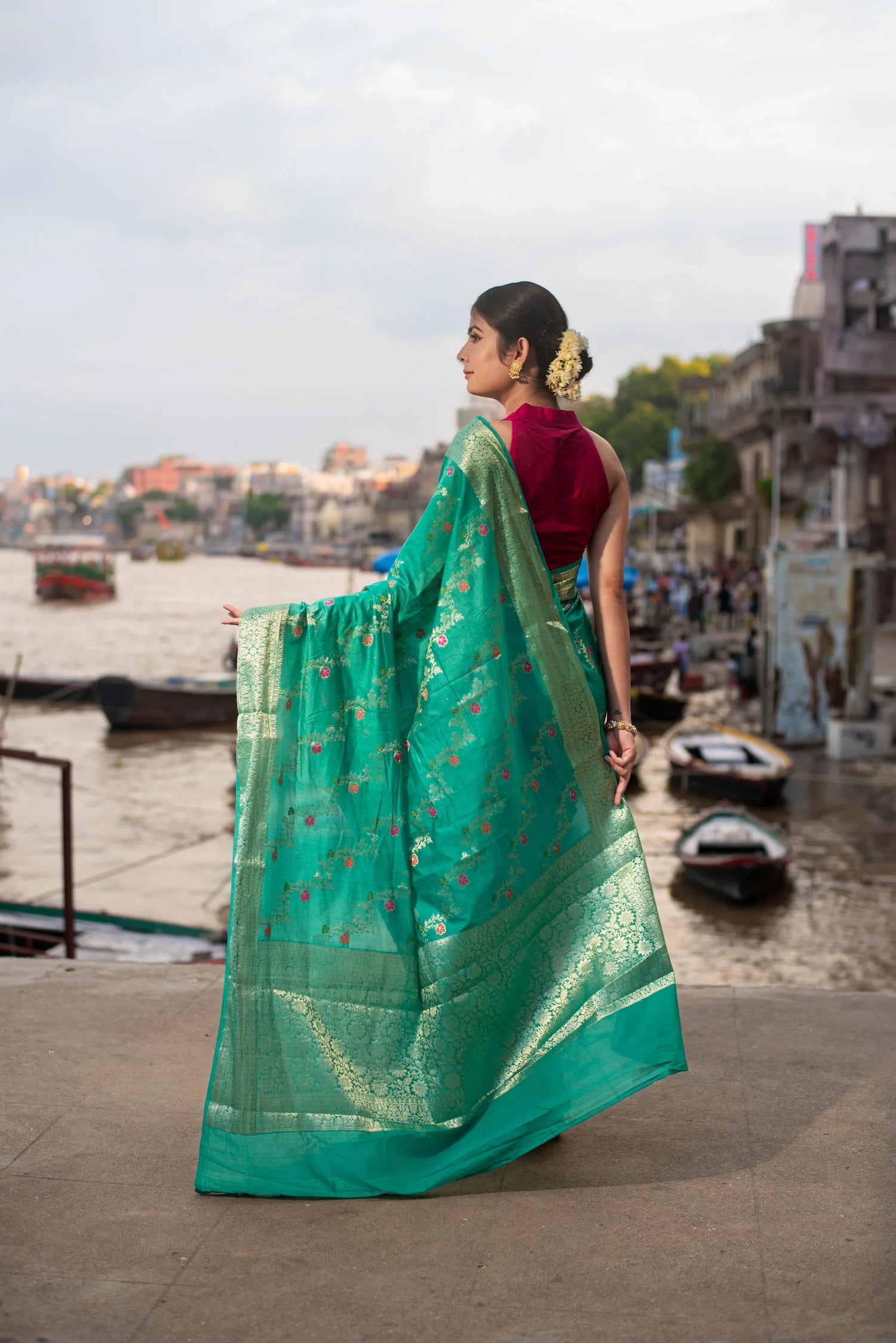 Woman in green Banarasi silk saree with Meenakari work by riverside ghat