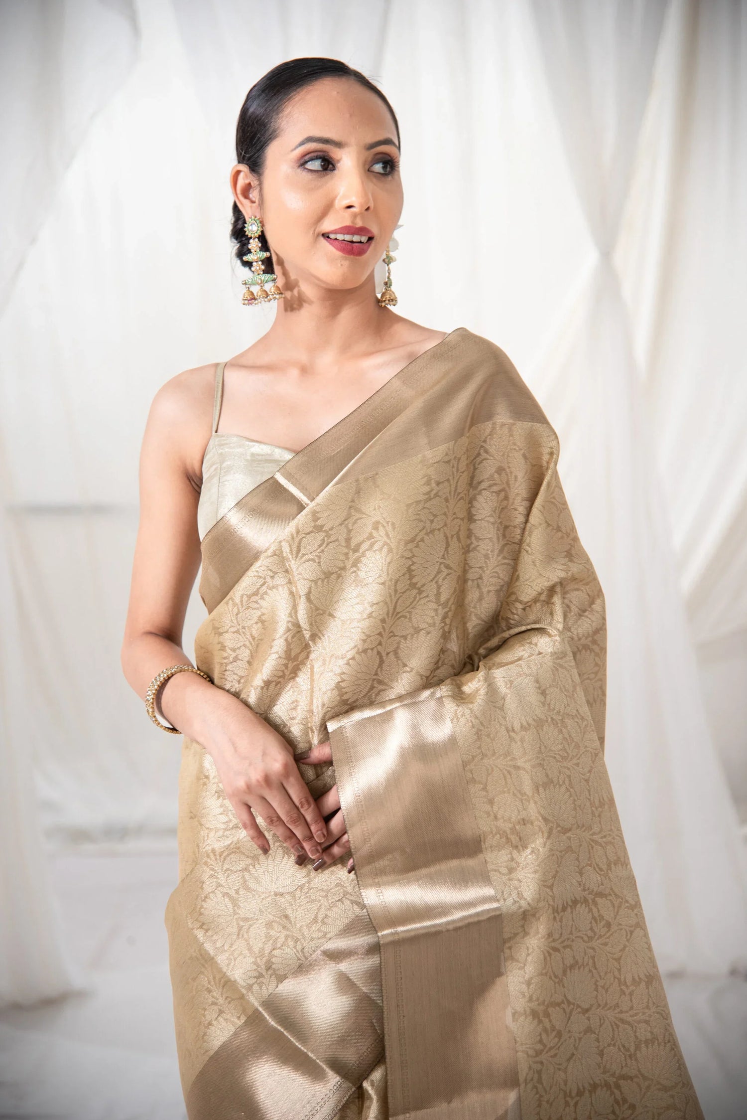 Woman wearing gold Banarasi silk saree with floral pattern in elegant indoor setting